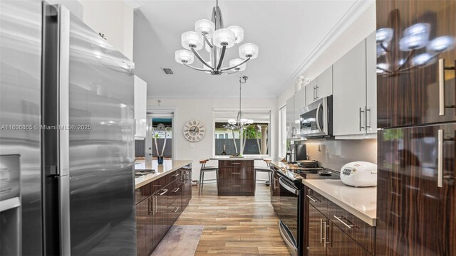 8775 NW 168th St, Miami Lakes, FL 33018 - kitchen with stainless steel appliances, a chandelier, modern cabinets, dark brown cabinetry, and crown molding