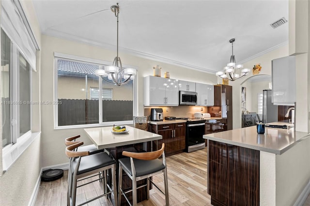 8775 NW 168th St, Miami Lakes, FL 33018 - kitchen with appliances with stainless steel finishes, a chandelier, ornamental molding, arched walkways, and light countertops