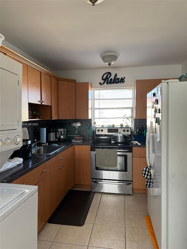 2651 NW 13th St Unit 45, Miami, FL 33125 - kitchen with freestanding refrigerator, electric stove, estacked washer and dryer, dark countertops, and light tile patterned floors
