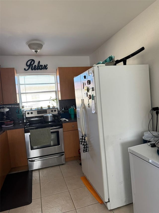 2651 NW 13th St Unit 45, Miami, FL 33125 - kitchen with electric range, freestanding refrigerator, light tile patterned floors, and brown cabinetry