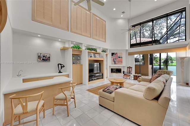 1910 Preston Trl, Coral Springs, FL 33071 - living area with a ceiling fan, a high ceiling, light tile patterned floors, built in features, and a tiled fireplace