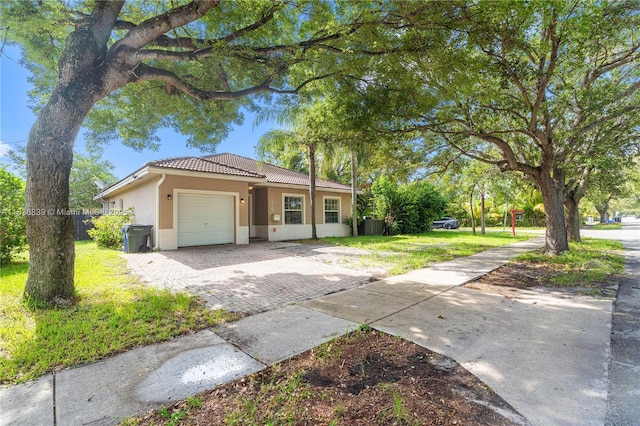 955 S 26th Ave, Hollywood, FL 33020 - view of front of home with decorative driveway, an attached garage, stucco siding, a tiled roof, and a front lawn