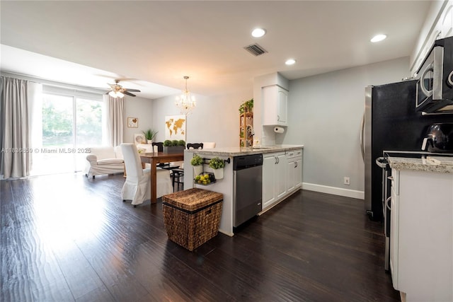 1606 Veracruz Ln, Weston, FL 33327 - kitchen with stainless steel appliances, a peninsula, dark wood-style flooring, white cabinets, and a chandelier