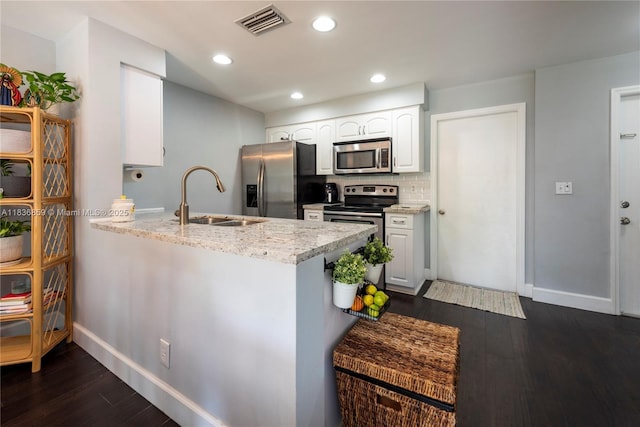 1606 Veracruz Ln, Weston, FL 33327 - kitchen with stainless steel appliances, a peninsula, light stone countertops, dark wood finished floors, and white cabinetry