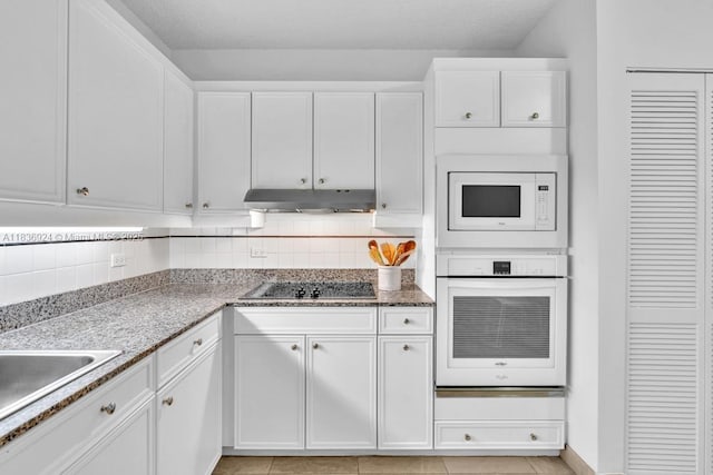 8855 E Collins Ave Unit 2F, Surfside, FL 33154 - kitchen featuring white appliances, under cabinet range hood, white cabinetry, tasteful backsplash, and stone counters
