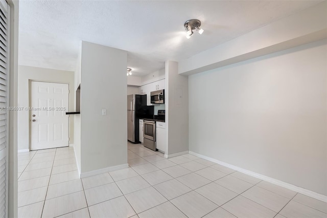 12136 Saint Andrews Pl Unit 204, Miramar, FL 33025 - kitchen featuring appliances with stainless steel finishes, white cabinets, light tile patterned floors, and dark countertops