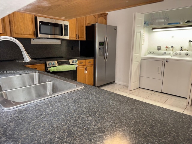 5201 SW 31st Ave Unit 112, Dania Beach, FL 33312 - kitchen featuring appliances with stainless steel finishes, washer and clothes dryer, brown cabinets, and dark countertops