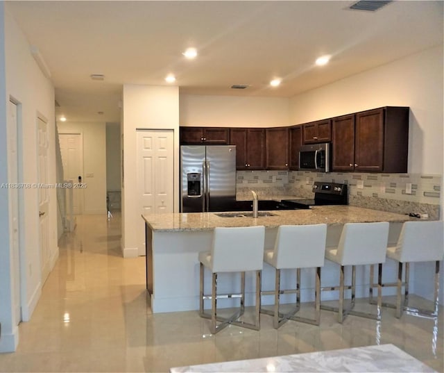 10498 W 33rd Way, Hialeah, FL 33018 - kitchen featuring stainless steel appliances, a peninsula, a breakfast bar area, tasteful backsplash, and recessed lighting