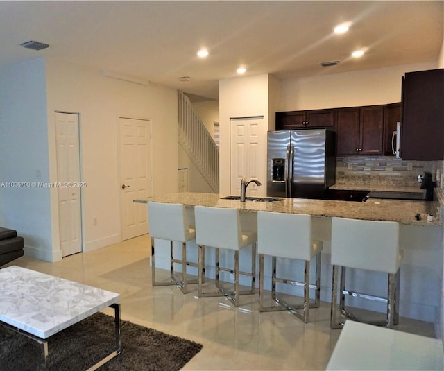 10498 W 33rd Way, Hialeah, FL 33018 - kitchen with appliances with stainless steel finishes, a kitchen bar, dark brown cabinets, recessed lighting, and light stone countertops