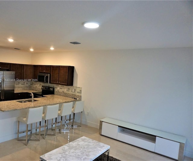 10498 W 33rd Way, Hialeah, FL 33018 - kitchen featuring appliances with stainless steel finishes, a breakfast bar area, decorative backsplash, dark brown cabinets, and a peninsula