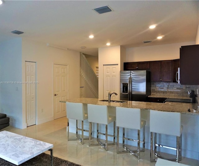 10498 W 33rd Way, Hialeah, FL 33018 - kitchen with stainless steel fridge with ice dispenser, stove, a breakfast bar, dark brown cabinetry, and light stone counters