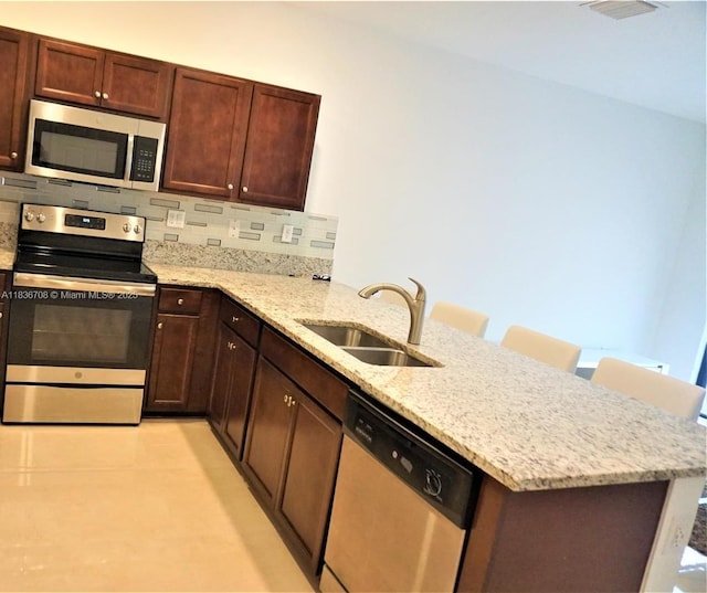 10498 W 33rd Way, Hialeah, FL 33018 - kitchen with stainless steel appliances, a peninsula, light stone countertops, and decorative backsplash