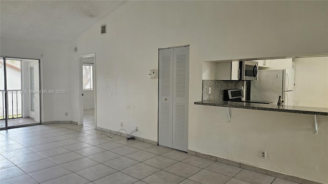 9277 SW 138th Pl Unit 9277, Miami, FL 33186 - kitchen featuring stainless steel microwave, freestanding refrigerator, light tile patterned flooring, range, and white cabinets