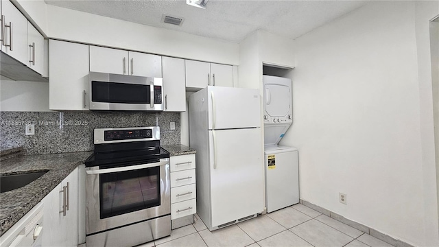 9277 SW 138th Pl Unit 9277, Miami, FL 33186 - kitchen featuring stainless steel appliances, estacked washer and dryer, tasteful backsplash, white cabinets, and light tile patterned flooring