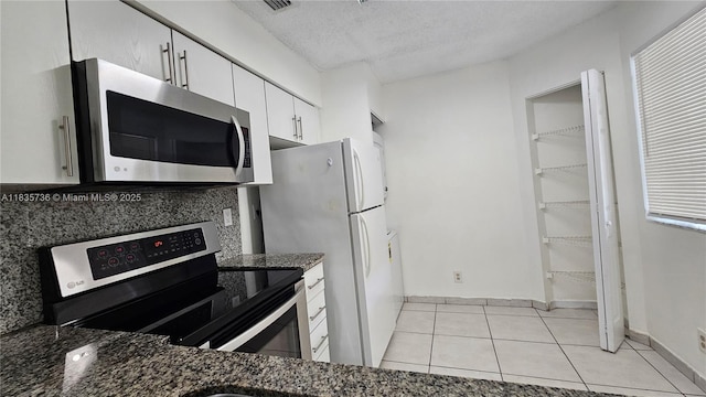9277 SW 138th Pl Unit 9277, Miami, FL 33186 - kitchen featuring appliances with stainless steel finishes, white cabinetry, light tile patterned floors, dark stone counters, and a textured ceiling