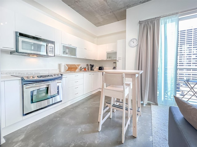 133 NE 2nd Ave Unit 1410, Miami, FL 33132 - kitchen with appliances with stainless steel finishes, concrete flooring, plenty of natural light, and white cabinets