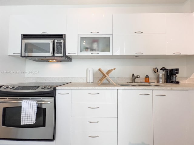 133 NE 2nd Ave Unit 1410, Miami, FL 33132 - kitchen with stainless steel appliances, white cabinets, modern cabinets, light countertops, and glass insert cabinets