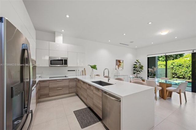3070 Elizabeth St, Miami, FL 33133 - kitchen featuring stainless steel appliances, modern cabinets, a peninsula, light countertops, and light tile patterned floors