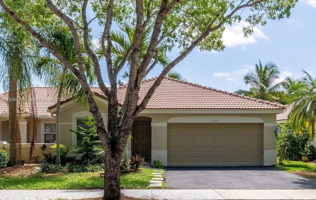 2020 Andromeda Ln, Weston, FL 33327 - mediterranean / spanish-style house with stucco siding, an attached garage, a tile roof, and asphalt driveway