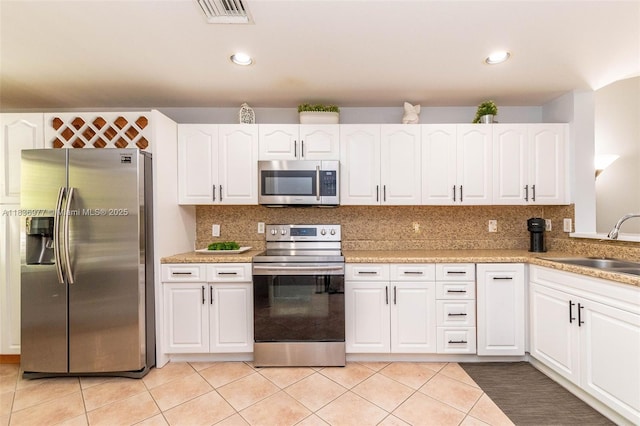 2020 Andromeda Ln, Weston, FL 33327 - kitchen with stainless steel appliances, white cabinets, decorative backsplash, light tile patterned flooring, and recessed lighting