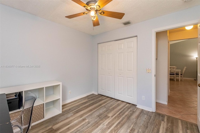 2020 Andromeda Ln, Weston, FL 33327 - unfurnished bedroom featuring a closet, wood finished floors, a textured ceiling, a ceiling fan, and a desk