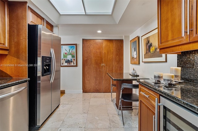 520 Brickell Key Dr Unit A1404, Miami, FL 33131 - kitchen with appliances with stainless steel finishes, beverage cooler, recessed lighting, brown cabinetry, and dark stone countertops