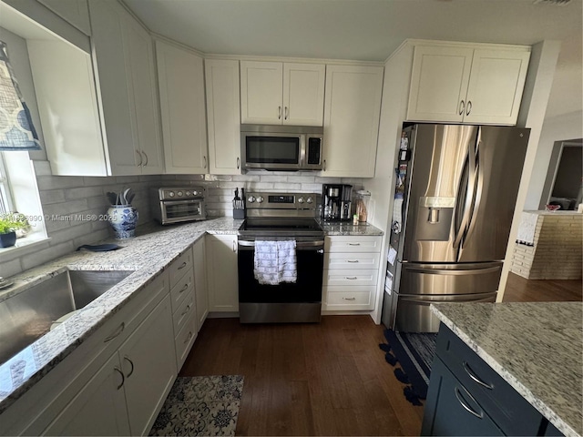 4621 NE 2nd Ave, Oakland Park, FL 33334 - kitchen with appliances with stainless steel finishes, dark wood-type flooring, tasteful backsplash, light stone countertops, and white cabinetry