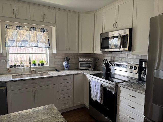 4621 NE 2nd Ave, Oakland Park, FL 33334 - kitchen featuring appliances with stainless steel finishes, backsplash, light stone countertops, dark wood finished floors, and white cabinets