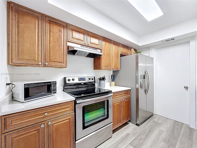 1309 SW 75th Ave, North Lauderdale, FL 33068 - kitchen featuring stainless steel appliances, under cabinet range hood, light wood-style flooring, and brown cabinetry
