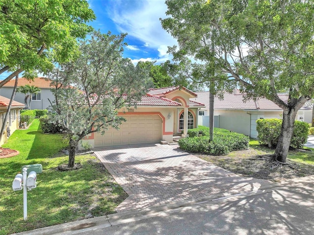 mediterranean / spanish home featuring an attached garage, a tile roof, stucco siding, decorative driveway, and a front yard