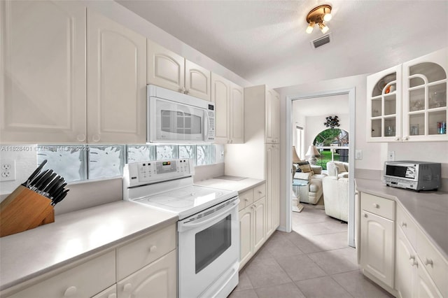 kitchen featuring white appliances, light countertops, glass insert cabinets, light tile patterned floors, and white cabinets