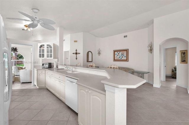 kitchen with white appliances, a peninsula, light tile patterned flooring, a ceiling fan, and arched walkways