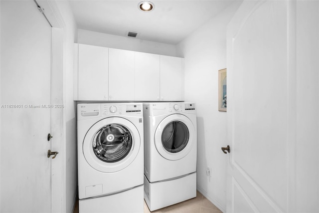 washroom with washing machine and dryer, cabinet space, and light tile patterned flooring