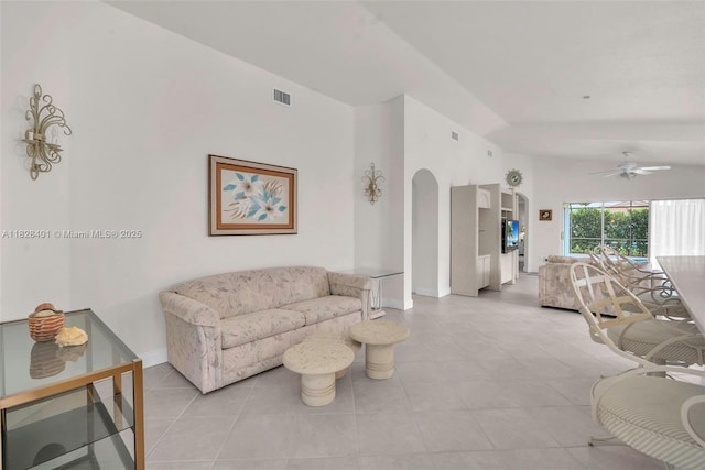 living area with arched walkways, ceiling fan, light tile patterned floors, and vaulted ceiling