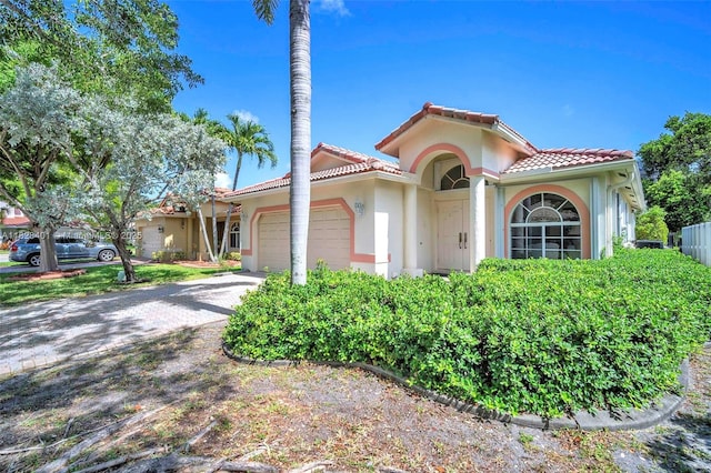 mediterranean / spanish home with a tiled roof, an attached garage, stucco siding, and driveway