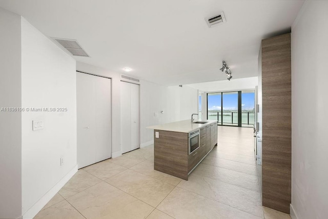 650 NE 32nd St Unit 2205, Miami, FL 33137 - kitchen featuring modern cabinets, an island with sink, light countertops, a wall of windows, and track lighting