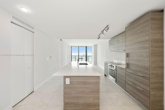 650 NE 32nd St Unit 2205, Miami, FL 33137 - kitchen featuring modern cabinets, oven, an island with sink, light countertops, and black electric stovetop