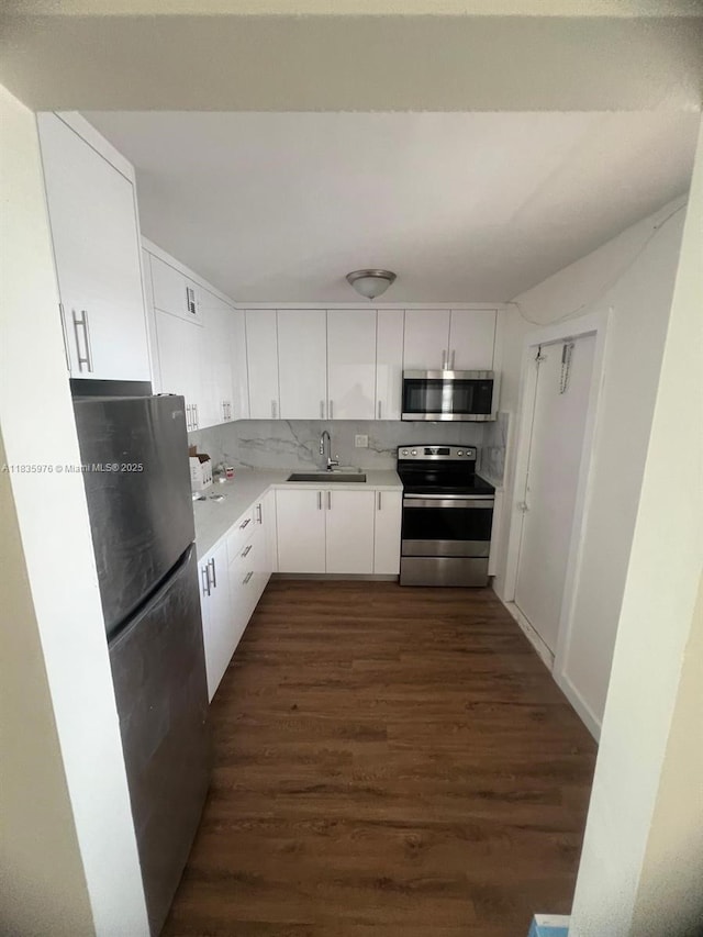 14180 SW 84th St Unit 407-G, Miami, FL 33183 - kitchen featuring stainless steel appliances, white cabinetry, dark wood-type flooring, light countertops, and decorative backsplash