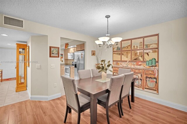 801 SW 138th Ave Unit 103E, Pembroke Pines, FL 33027 - dining space featuring a chandelier, light wood-style flooring, and a textured ceiling