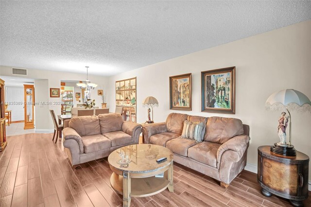 801 SW 138th Ave Unit 103E, Pembroke Pines, FL 33027 - living room featuring light wood-style flooring, a chandelier, and a textured ceiling
