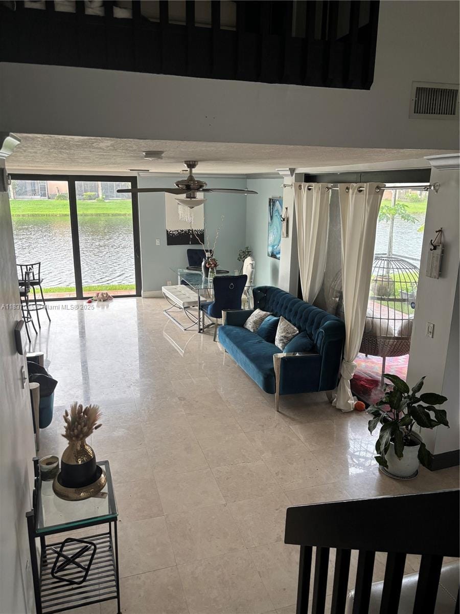 living area with ceiling fan and a water view