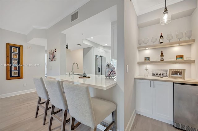 7588 SW 102nd St Unit 203, Pinecrest, FL 33156 - kitchen featuring stainless steel refrigerator, stainless steel fridge with ice dispenser, light wood-type flooring, a breakfast bar area, and ornamental molding