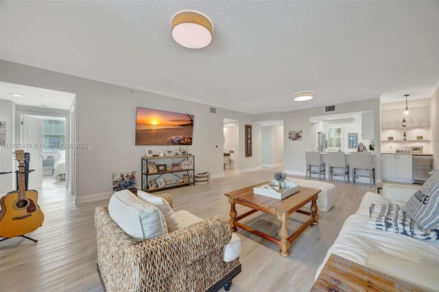 7588 SW 102nd St Unit 203, Pinecrest, FL 33156 - kitchen featuring appliances with stainless steel finishes, under cabinet range hood, open floor plan, open shelves, and light wood-type flooring
