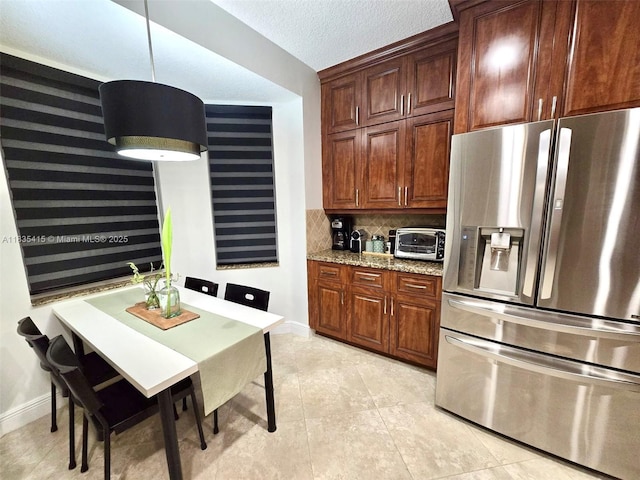 547 Cascade Falls Dr, Weston, FL 33327 - kitchen with stainless steel fridge, decorative backsplash, light stone counters, light tile patterned floors, and pendant lighting
