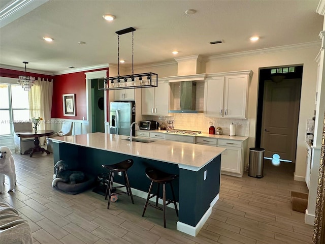 799 Hookline Cir, Loxahatchee, FL 33470 - kitchen with wall chimney range hood, stainless steel appliances, a breakfast bar area, light countertops, and white cabinets