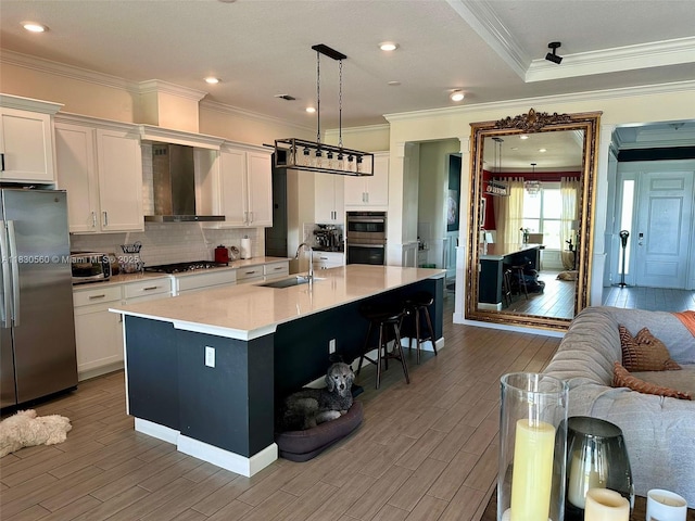 799 Hookline Cir, Loxahatchee, FL 33470 - kitchen with stainless steel appliances, wall chimney range hood, wood finished floors, white cabinets, and backsplash