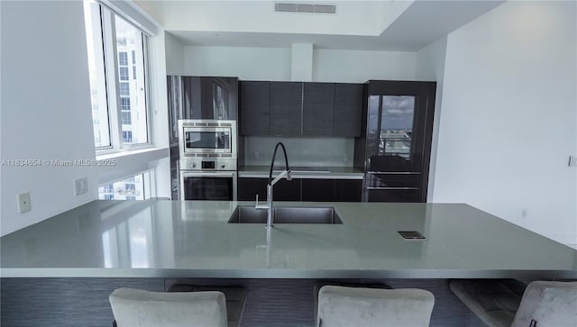 1080 Brickell Ave Unit 4209, Miami, FL 33131 - kitchen featuring appliances with stainless steel finishes, a kitchen breakfast bar, light countertops, modern cabinets, and dark cabinetry