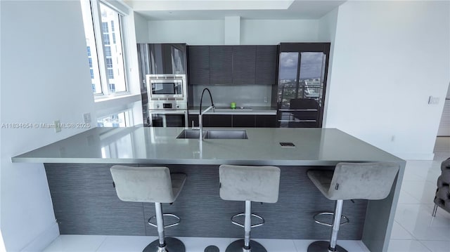 1080 Brickell Ave Unit 4209, Miami, FL 33131 - kitchen featuring appliances with stainless steel finishes, a kitchen breakfast bar, modern cabinets, light countertops, and light tile patterned floors