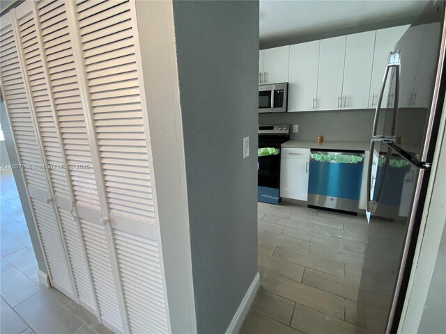 2025 NE 164th St Unit 807, North Miami Beach, FL 33162 - kitchen with stainless steel appliances, light tile patterned floors, and white cabinets