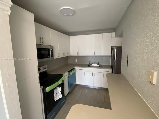 2025 NE 164th St Unit 807, North Miami Beach, FL 33162 - kitchen with stainless steel microwave, black electric range oven, freestanding refrigerator, dishwasher, and a textured wall